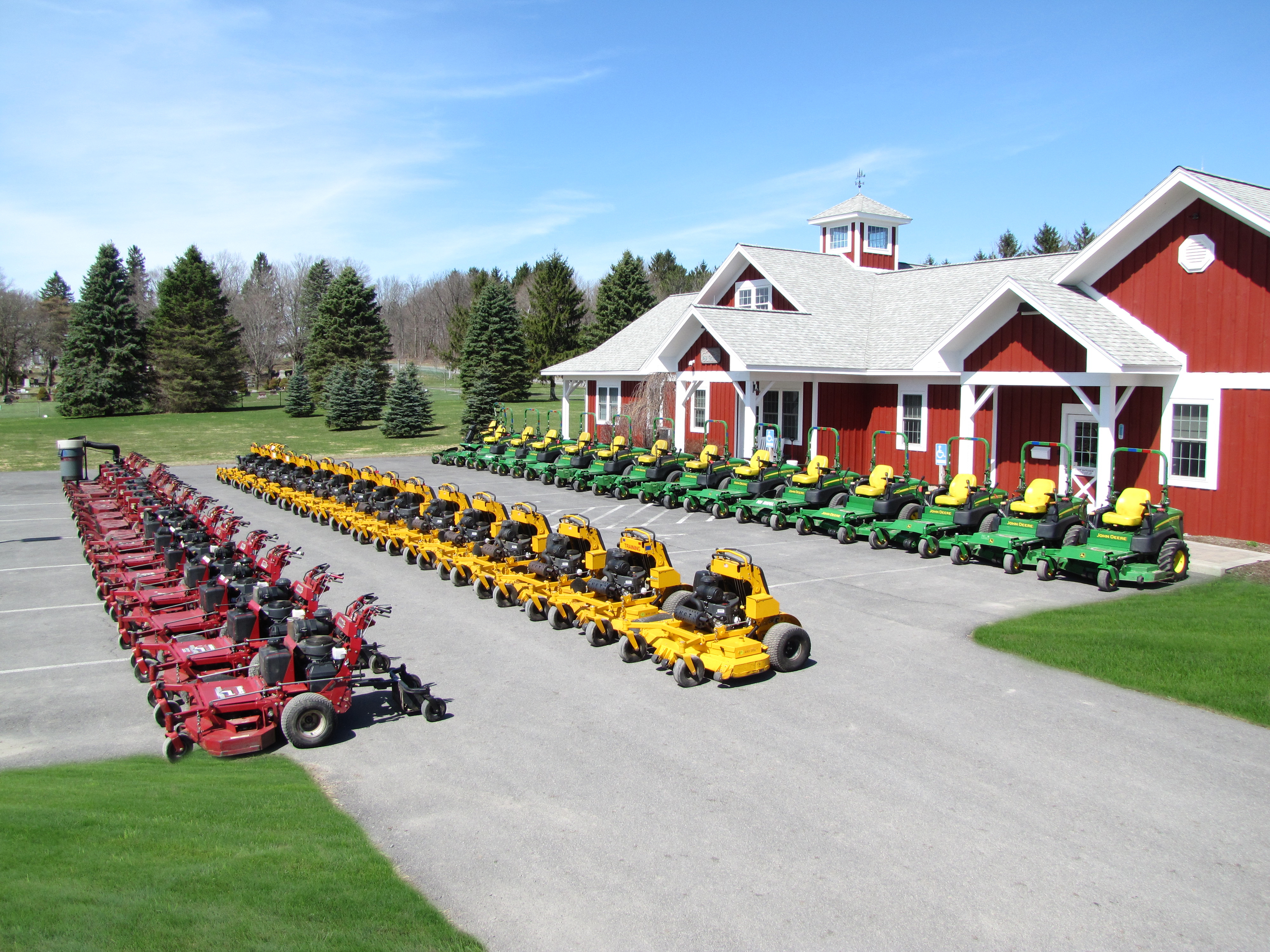 A picture of many Pro Scapes Inc. lawn mowed lined up in front of the Pro Scapes office building.